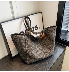 Detalle del bolso tote de lona con estampado de leopardo, remaches y etiqueta de cuero