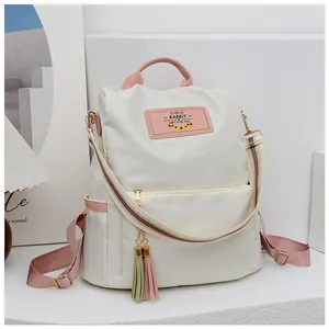 Détail du sac à dos en tissu Oxford avec sangles roses et pompon décoratif sur le devant