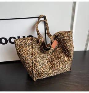 Detalle de bolso tote de lona con leopardo, etiqueta de cuero marrón y remaches de refuerzo