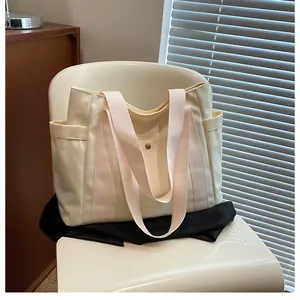 Detail view of cream canvas tote bag with pink straps on a chair in soft natural light