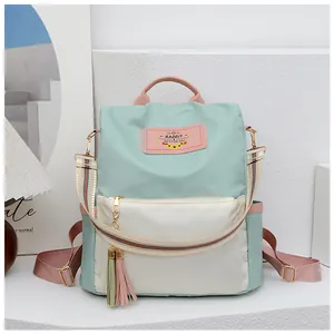 Détail du sac à dos Oxford tricolore avec pompons et poches sur fond de décoration épurée