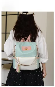 Détail d'un sac à dos en nylon bicolore avec pompon et fermetures éclair dorées