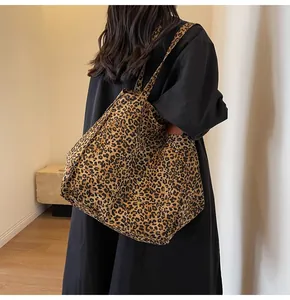 Primer plano del bolso tote de lona con estampado de leopardo y detalle de cuero marrón
