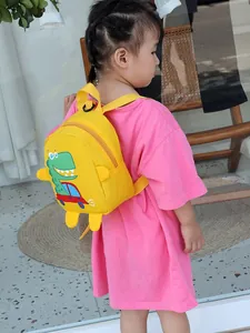 Kids yellow canvas backpack with cartoon dinosaur print worn by a child on pink shirt