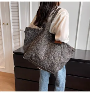 Detalle de un bolso tote grande de lona con estampado de leopardo y tachuelas metálicas