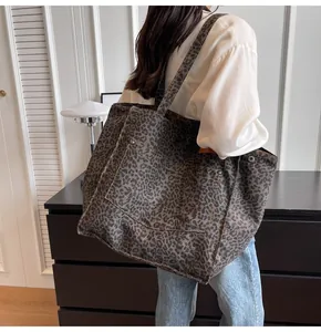 Vista lateral de un bolso tote de lona con estampado de leopardo y bolsillo con remaches