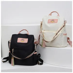 Détails de sacs à dos en nylon noir et beige avec sangles rayées et pompons déco