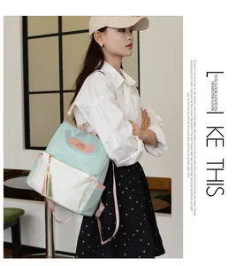 Détail du sac à dos oxford bleu et beige avec sangles roses et pompon décoratif
