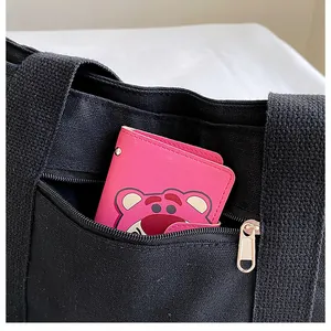 Cartera rosa de Lotso en el bolsillo delantero con cremallera de un bolso de lona negra