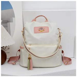 Détail du sac à dos oxford montrant l'étiquette en cuir rose et les pompons