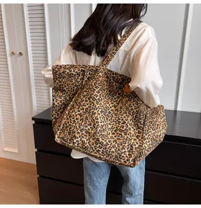 Vista lateral de bolsa tote de lona con estampado de leopardo y cierre de presión de metal