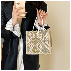 Detail of geometric embroidery and wooden button closure on a linen canvas tote bag