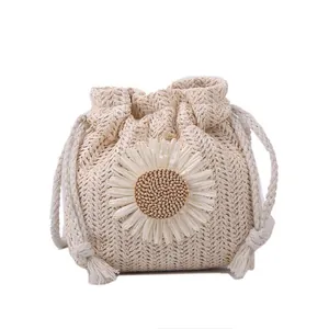 Woven straw bucket bag with white daisy decoration and tassel drawstring for women
