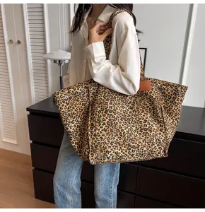 Detalle del bolso tote grande de lona con estampado de leopardo y hebillas de metal