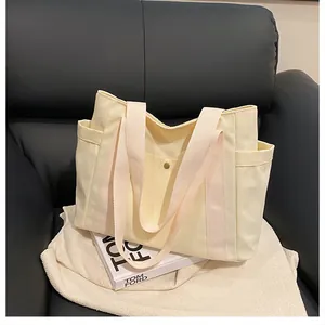 Vista detallada del bolso tote de lona beige con correas rosas sobre un sofá