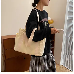 Close-up of the wide fabric shoulder strap and side pocket on a cream canvas tote bag