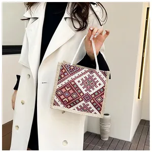 Detailed embroidery on a linen tote bag with colorful ethnic patterns and rope handle