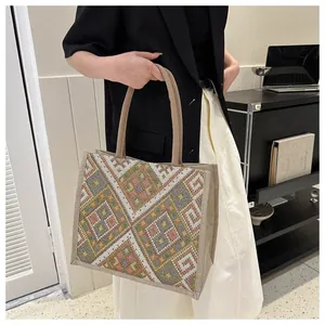 Primer plano del bordado étnico geométrico en un gran bolso tote de lona beige con asas