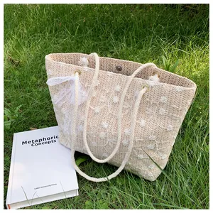 Detail der Strohtasche mit floraler Stickerei und dekorativem Schleifen-Ornament