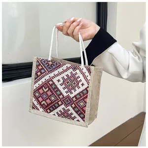 Detail of bohemian geometric tapestry on natural burlap tote bag with cotton rope handles