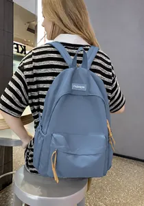 Detail of light blue waterproof nylon backpack with fashion label and orange puller