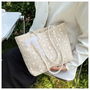 Detailaufnahme der Strohtasche mit Blumenstickerei und Spitzenschleife für Damen