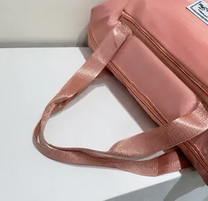 Detail of pink foldable travel bag showing durable handles and high quality fabric texture