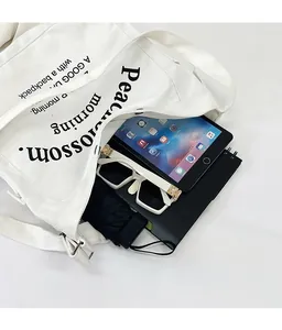 Détail montrant la grande capacité du sac fourre-tout en toile avec tablette et objets