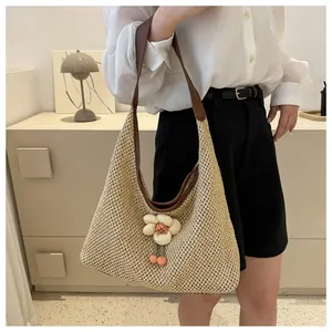 Detalle del bolso tote de paja tejido con asa de cuero y colgante de flor rosa