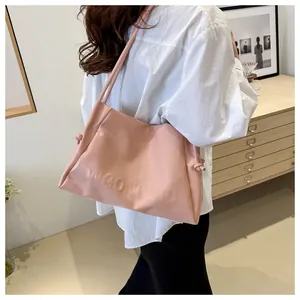 Detailed close-up of pink tote bag with embossed letters and double shoulder straps