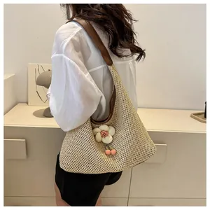 Detalle del bolso hobo tejido a mano con dijes florales y correa de cuero marrón