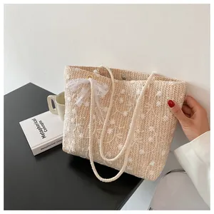 Detail der Strohtasche mit Blumenstickerei, Spitzenschleife und Seilgriff für Sommer