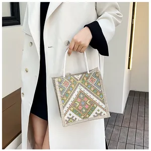 Close-up of bohemian geometric embroidery and cotton rope handles on a linen tote bag