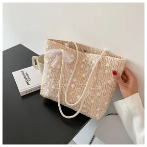 Detailansicht der beige geflochtenen Tragetasche mit Blumenstickerei und Spitzenschleife