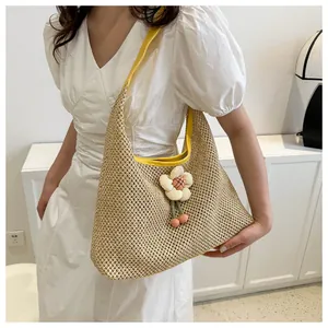 Detalle del bolso de hombro de paja tejida con ribete amarillo y colgante de flor