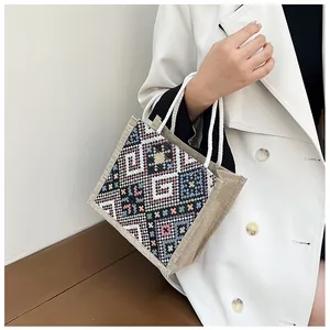 Close-up of ethnic canvas tote with geometric embroidery and white rope handles