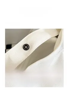 Détail du bouton-pression en métal de qualité sur un sac cabas en toile blanche