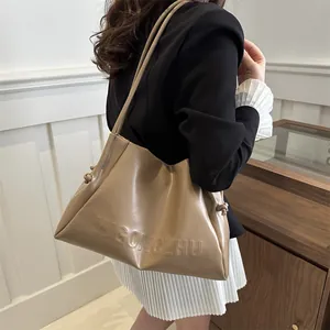 Chic beige large tote bag with embossed letters and side drawstring shown on a model