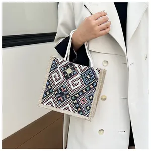 Close-up of ethnic geometric embroidery and woven cotton handles on a jute tote bag