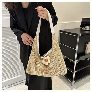Detalle del bolso tote de paja trenzada con correa blanca de imitación de cuero y dije