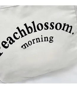 Détail du sac en toile blanc cassé montrant le lettrage noir et la texture du tissu épais