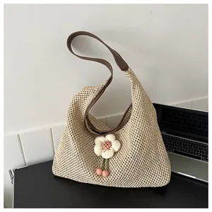 Detalle del bolso tote beige tejido a mano con correa de cuero y amuleto floral