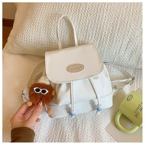 Mini white leather backpack with cute plush charm and elegant drawstring pocket detail