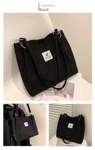 Detail view of black corduroy tote bag showing metal ring buckle and ribbed texture