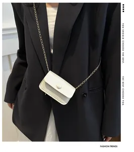 Detail view of mini cream white crossbody bag with gold chain strap on black blazer