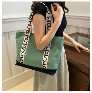 Détail latéral d'un grand sac fourre-tout en toile vert morandi avec sangle géométrique