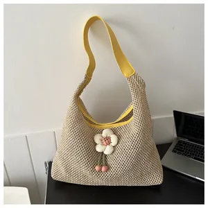 Detalle del bolso de paja tejido a mano con correa de cuero amarillo y adorno de flor
