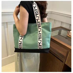 Détail du sac cabas en toile verte avec base noire et bandoulière à motifs