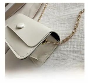 Detail view of beige PU leather crossbody bag featuring gold chain strap and punch-hole design