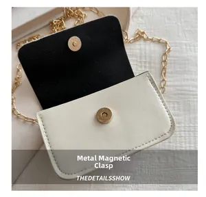 Detail of metal magnetic snap closure on a cream mini shoulder bag with chain